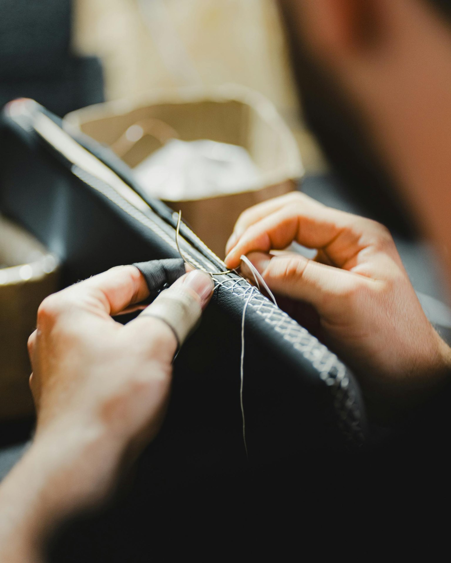 Mani di un artigiano al lavoro su cuoio cucito a mano